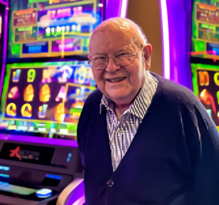 Len Ainsworth, an influential Australian businessman and founder of Aristocrat Leisure, stands proudly at a gaming convention, showcasing his legacy in the gaming industry.