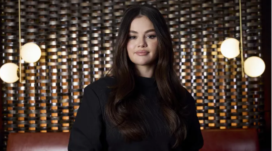 "Selena Gomez holding an award on stage, celebrating her achievements in music and acting."