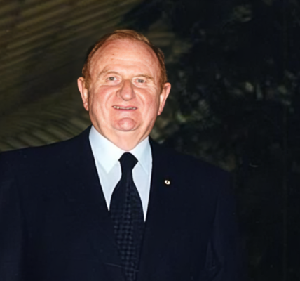 Portrait of John Gandel, renowned Australian businessman and philanthropist, standing in front of the Chadstone Shopping Centre, his major real estate development.