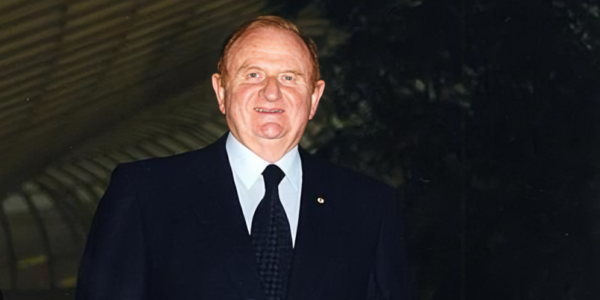 Portrait of John Gandel, renowned Australian businessman and philanthropist, standing in front of the Chadstone Shopping Centre, his major real estate development.