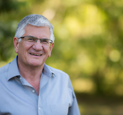 Peter Irvine, co-founder of Gloria Jean’s Coffees, smiling confidently in a business suit.