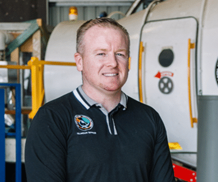 James Gilmour, founder of Gilmour Space Technologies, standing near a hybrid rocket engine