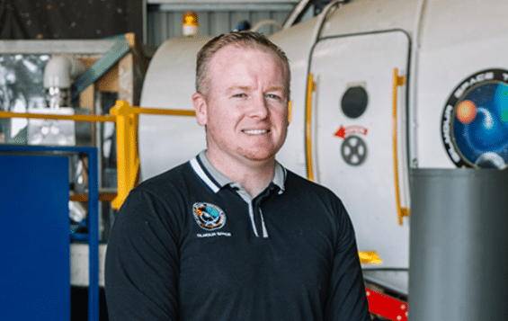 James Gilmour, founder of Gilmour Space Technologies, standing near a hybrid rocket engine